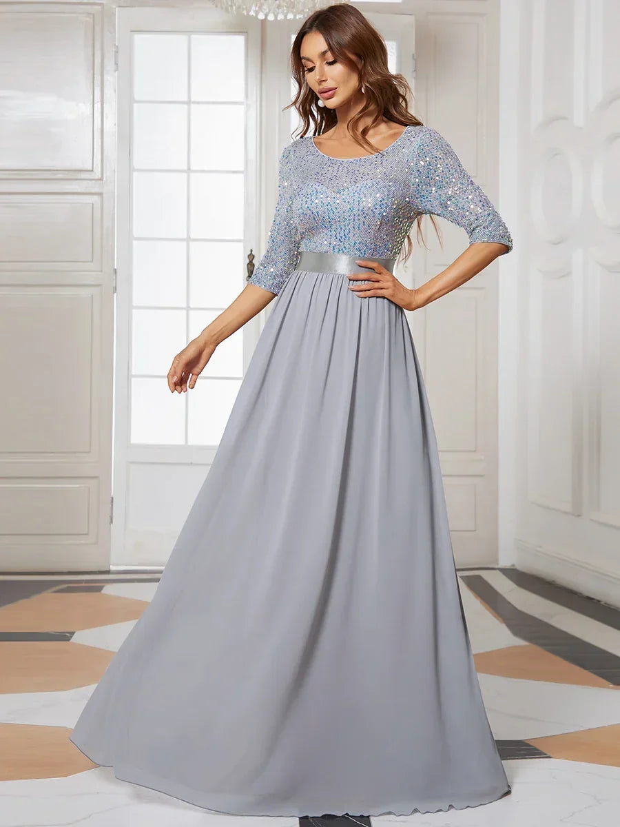 Woman wearing an elegant grey evening gown with a sequined bodice and flowing skirt.