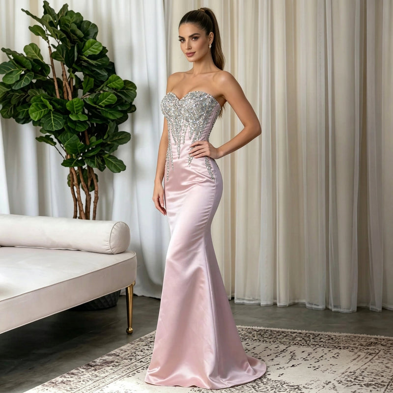Woman wearing a strapless pink satin mermaid gown with rhinestone embellishments by AliExpress