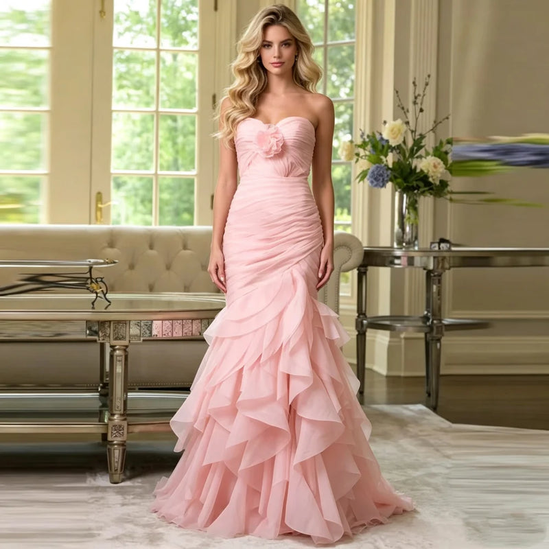 Woman wearing a pink strapless organza mermaid gown with tiered ruffles by Dream Designs Boutique