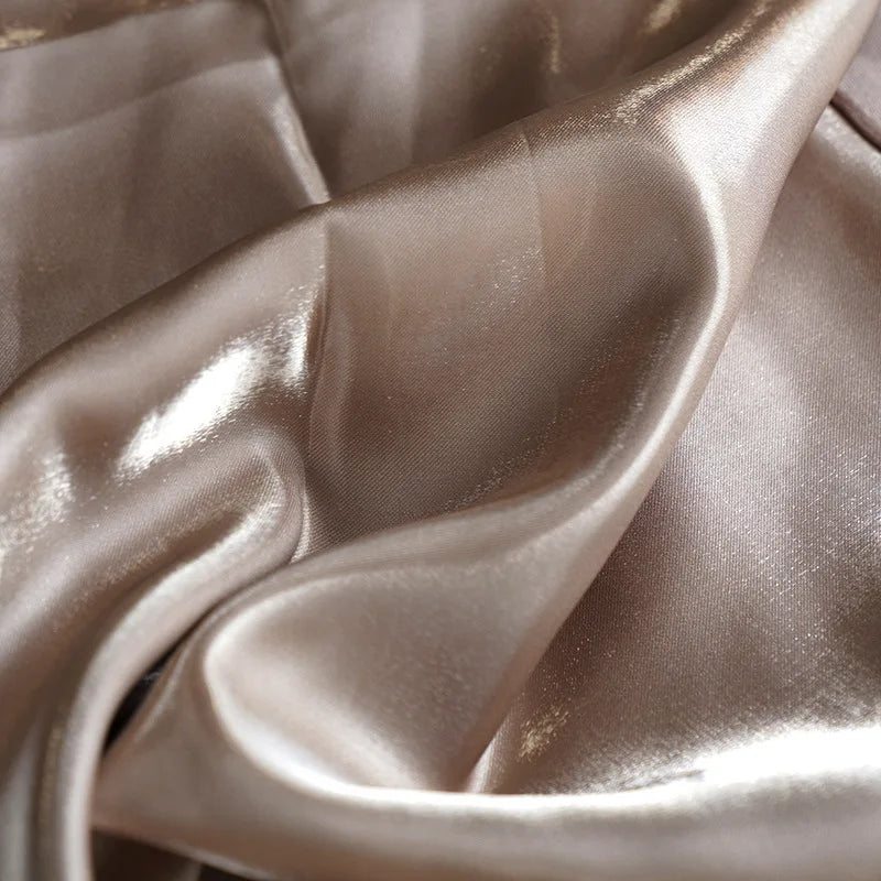 Close-up of luxurious champagne satin fabric with elegant flowing folds for evening gowns.