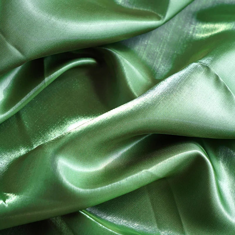 Lustrous green satin fabric with elegant folds and a shimmering texture.
