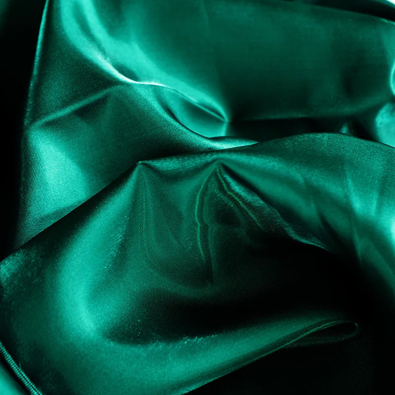 Lustrous emerald green satin fabric with elegant flowing folds and a silky texture.