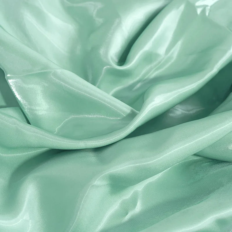 Smooth mint green satin fabric texture for elegant evening wear and prom dresses.