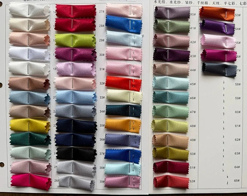 Assorted satin fabric color swatches in various shades for custom dress design.